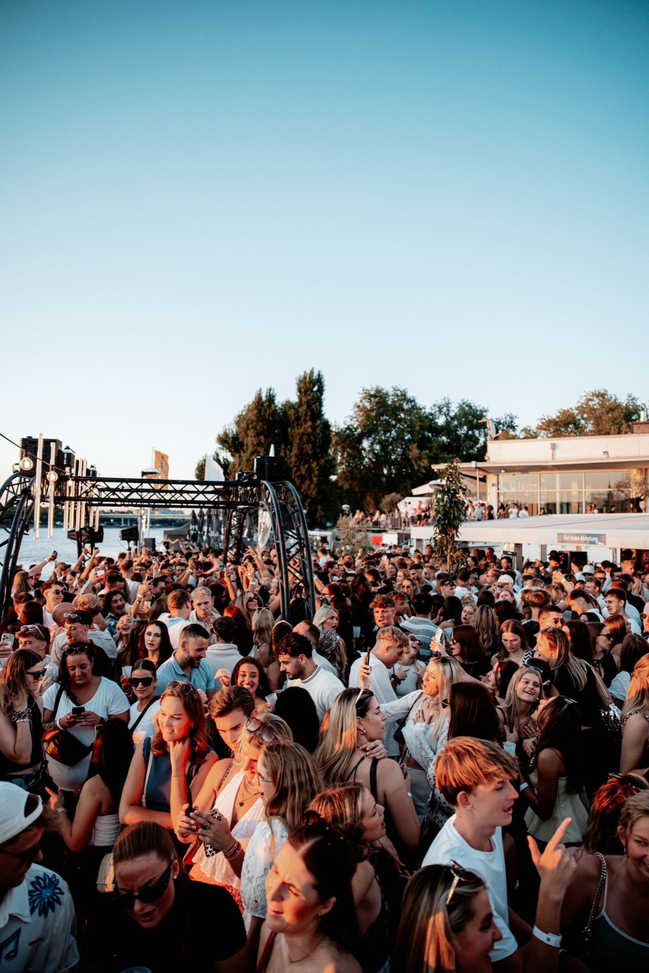 Volle Tanzfläche zur goldenen Stunde beim Golden Flame Open-Air an den Rheinterrassen, im Hintergrund der Rhein