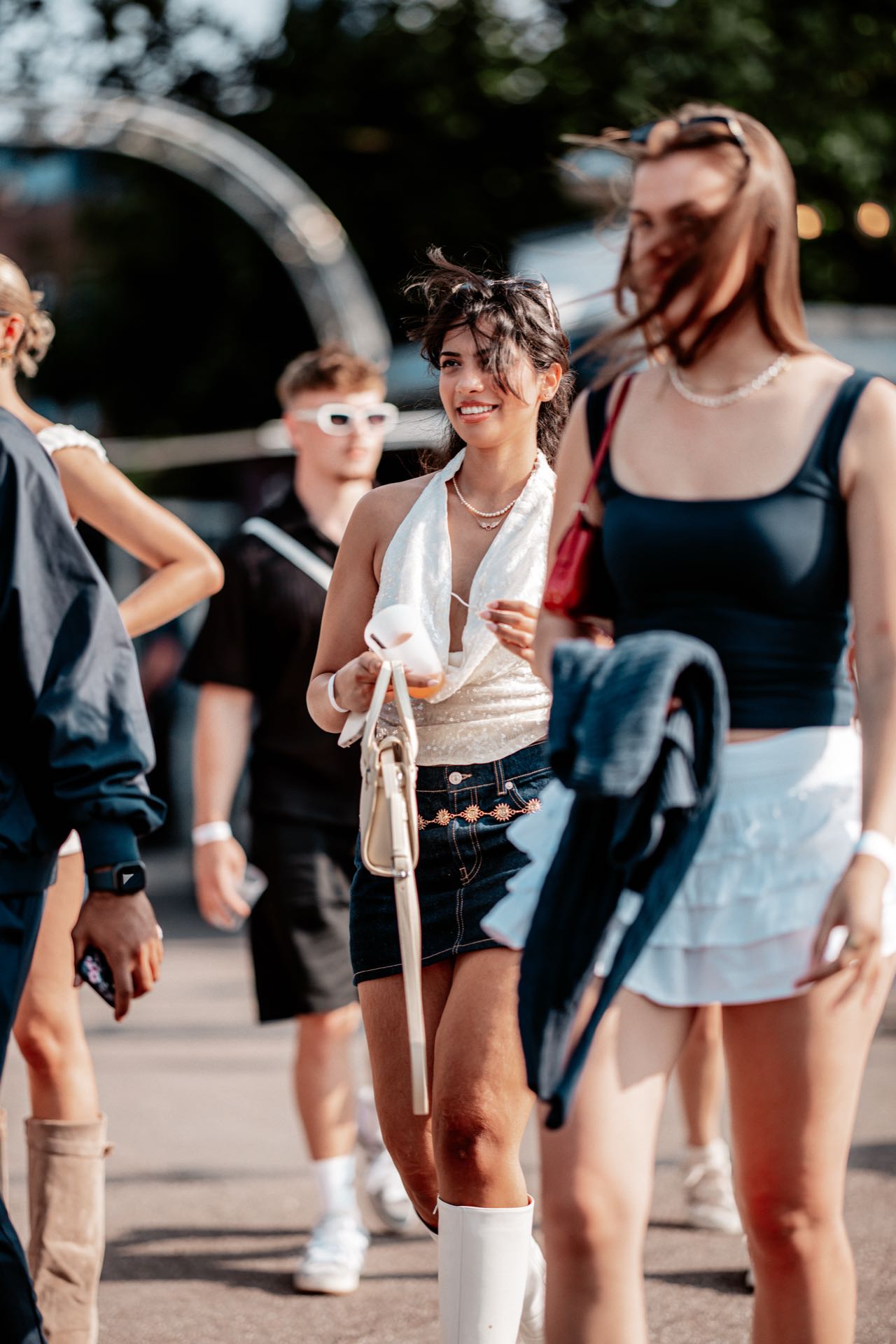 Junge Frau im Pailletten-Top kommt zur goldenen Stunde beim Open-Air an den Rheinterrassen Köln an