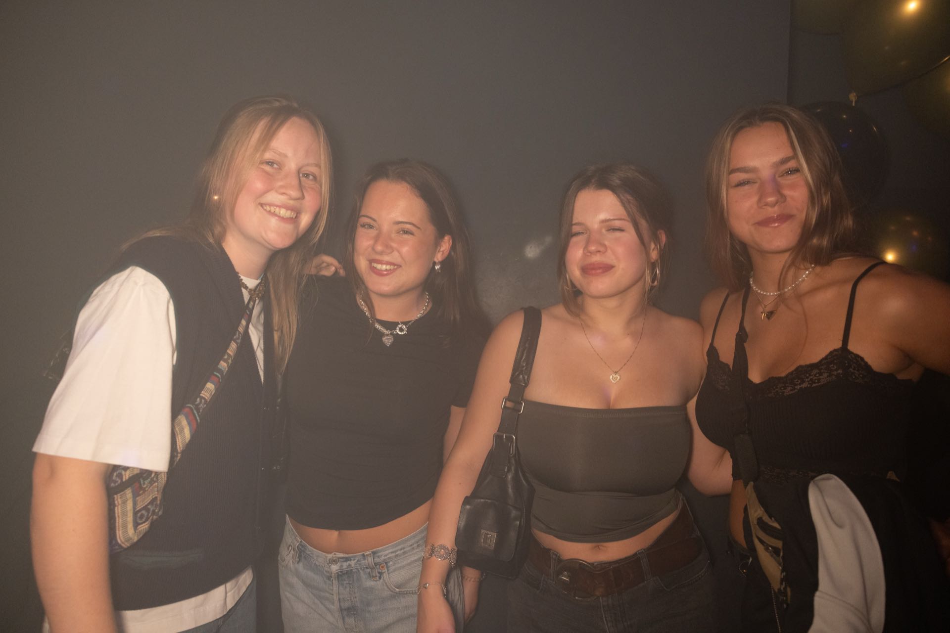 Vier Freundinnen in Jeans und schwarzen Tops bei einer Golden Flame Clubnacht in Köln