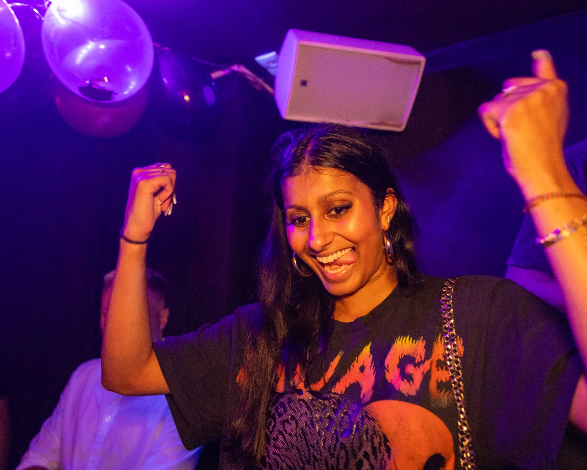 Frau tanzt mit erhobenen Armen und strahlt unter Luftballons bei einer Club-Nacht in Köln