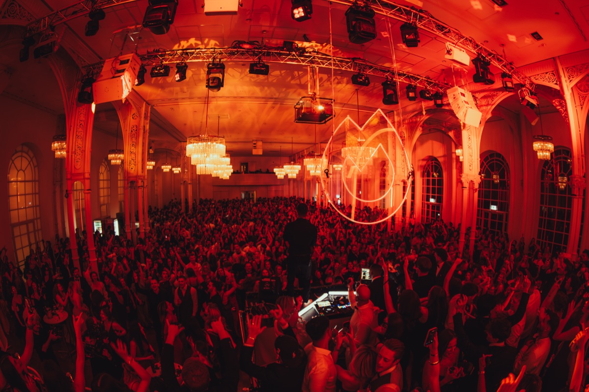 Warm beleuchteter Ballsaal mit Kronleuchtern und feiernder Crowd in der Flora Köln