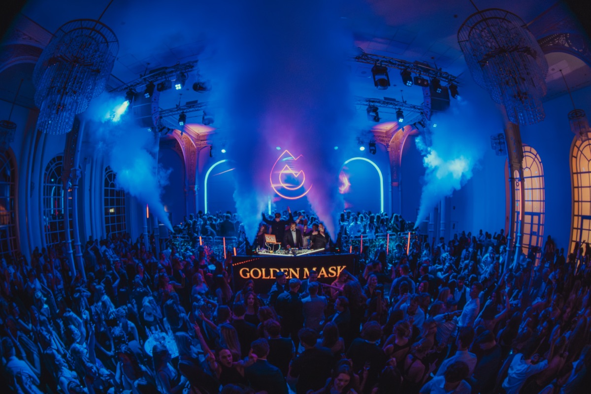 Golden Mask Maskenball in der Flora Köln, weite Halle in blauem Licht mit Kronleuchtern und Nebelfontänen