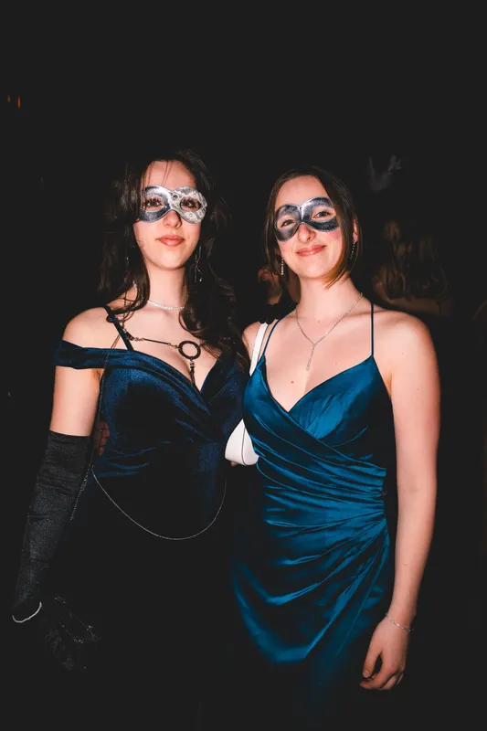 Zwei Frauen in petrolfarbenen Samtkleidern mit filigranen Spitzenmasken beim Golden Mask in der Flora Köln