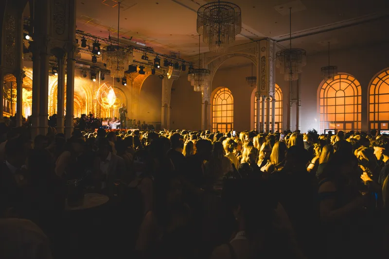 Warm beleuchteter Festsaal mit Kronleuchtern und tanzender Crowd beim Golden Mask in Köln