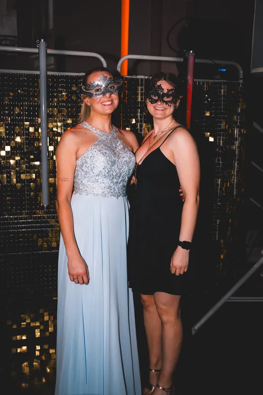Zwei Freundinnen mit silbernen Masken, eine in einer langen hellblauen Robe mit glitzerndem Oberteil, beim Golden Mask in der Flora Köln