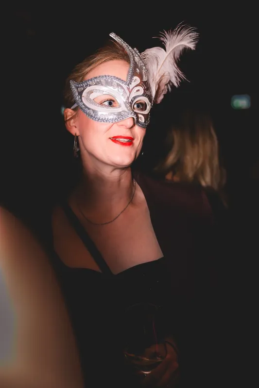Frau mit silberner Maske mit Federn und rotem Lippenstift beim Maskenball Golden Mask in der Flora Köln