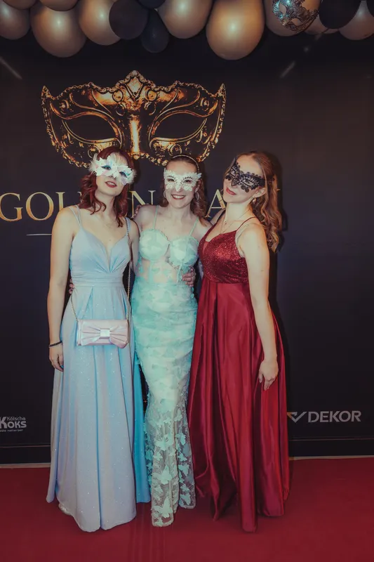 Drei Freundinnen in Hellblau, Mint mit Spitze und Bordeaux mit Masken auf dem roten Teppich beim Golden Mask