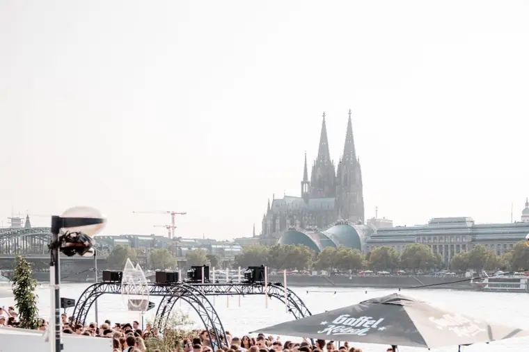 Kölner Dom über der Terrasse der Rheinterrassen mit Gästen in Weiß