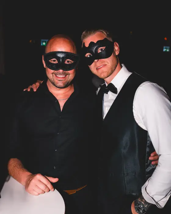 Zwei Männer mit schwarzen Halbmasken beim Golden Mask, einer in schwarzer Weste mit Fliege und weißem Hemd