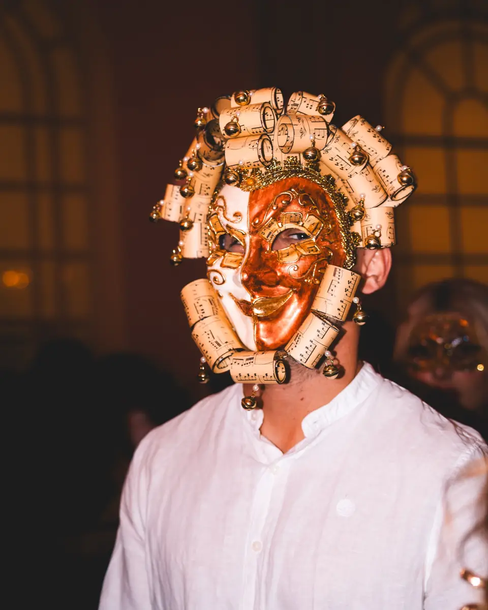 Gast mit goldener venezianischer Vollmaske voller Ornamente und weißem Hemd beim Maskenball Golden Mask in der Flora Köln