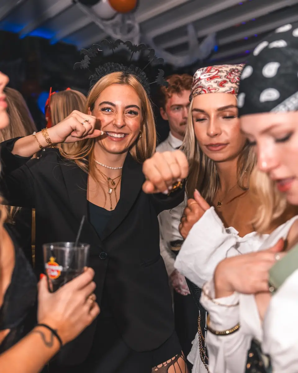 Zwei Freundinnen in schwarzen Blazern mit Fledermaus-Haarreif lachen bei Spooky Flame im Goldfinger Club Köln
