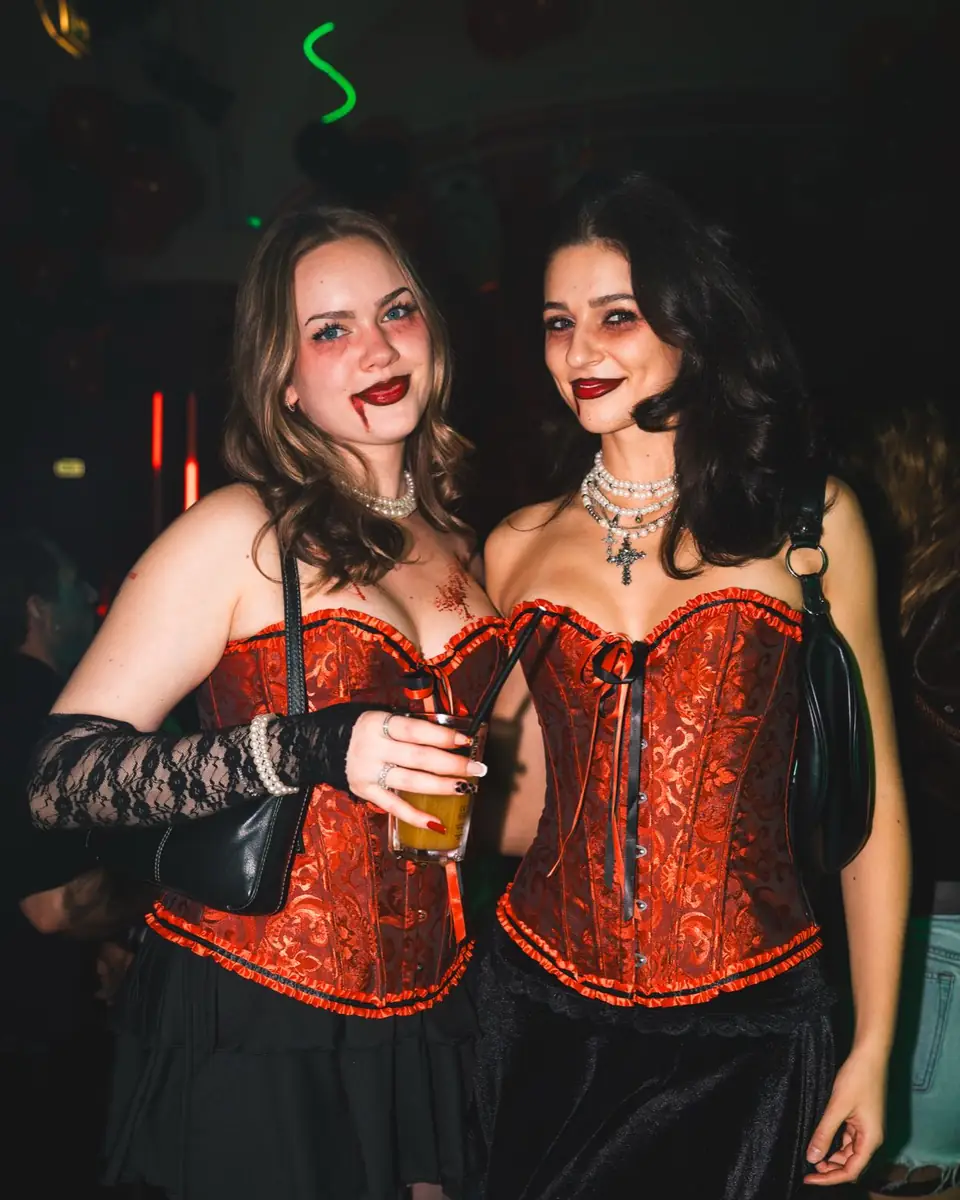 Zwei Freundinnen im Partnerlook mit roten Corsagen, schwarzen Röcken und Spitzenhandschuhen bei Spooky Flame in Köln