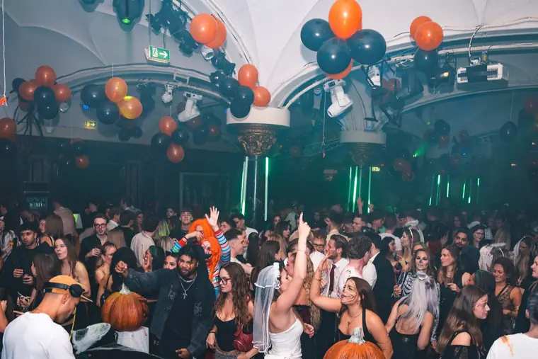 Volle Tanzfläche unter orange-schwarzen Ballons und grünem Licht bei Spooky Flame im Wartesaal am Dom in Köln