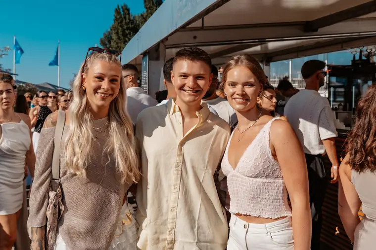 Three friends in relaxed summer outfits laughing into the camera at the Rheinterrassen in Cologne