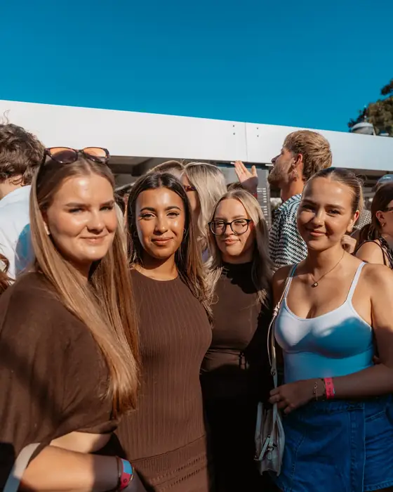 Vier Freundinnen stehen eng beieinander beim Golden Flame Open-Air an den Rheinterrassen Köln