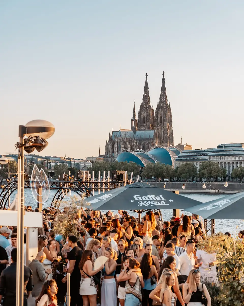 Blick von oben auf die Rheinterrassen Köln mit Dom und Crowd zur goldenen Stunde