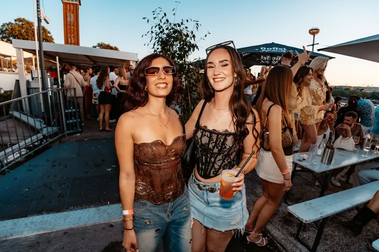 Zwei Freundinnen in Korsage-Tops und Jeansrock auf der Terrasse an den Rheinterrassen Köln