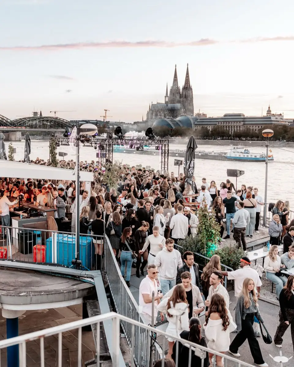 Blick über die Rheinterrassen auf Rhein, Hohenzollernbrücke und Kölner Dom am Abend