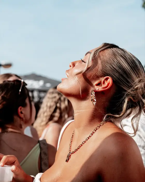 Frau mit Glow und goldenem Schmuck lacht in die Sonne beim Golden Flame Summer Opening