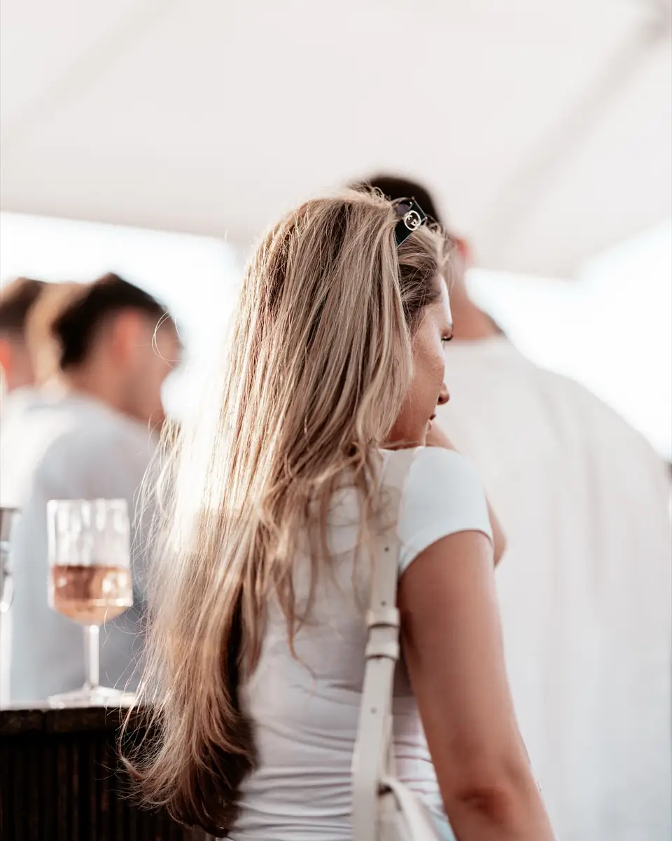 Frau mit langen, welligen Haaren von hinten auf der Terrasse beim Golden Flame Summer Opening in Köln