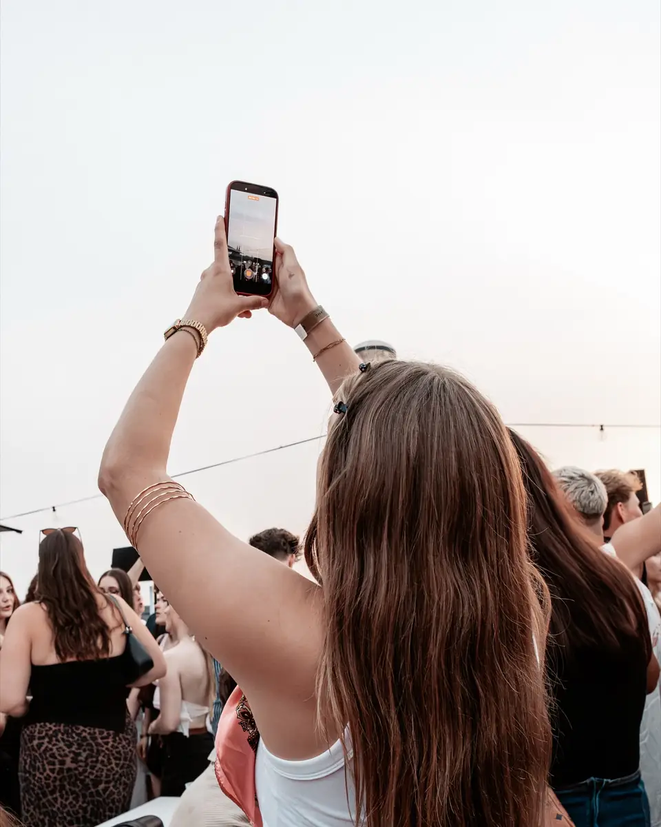 Frau von hinten fotografiert mit erhobenem Handy die Crowd beim Golden Flame Summer Opening