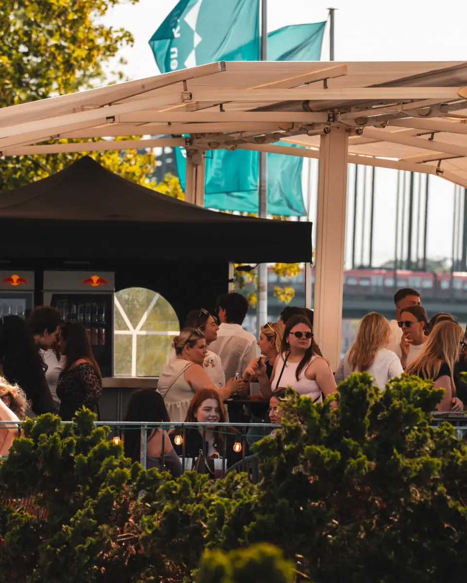 Große Sonnenschirme über einer ruhigen Terrasse am Rhein in Köln