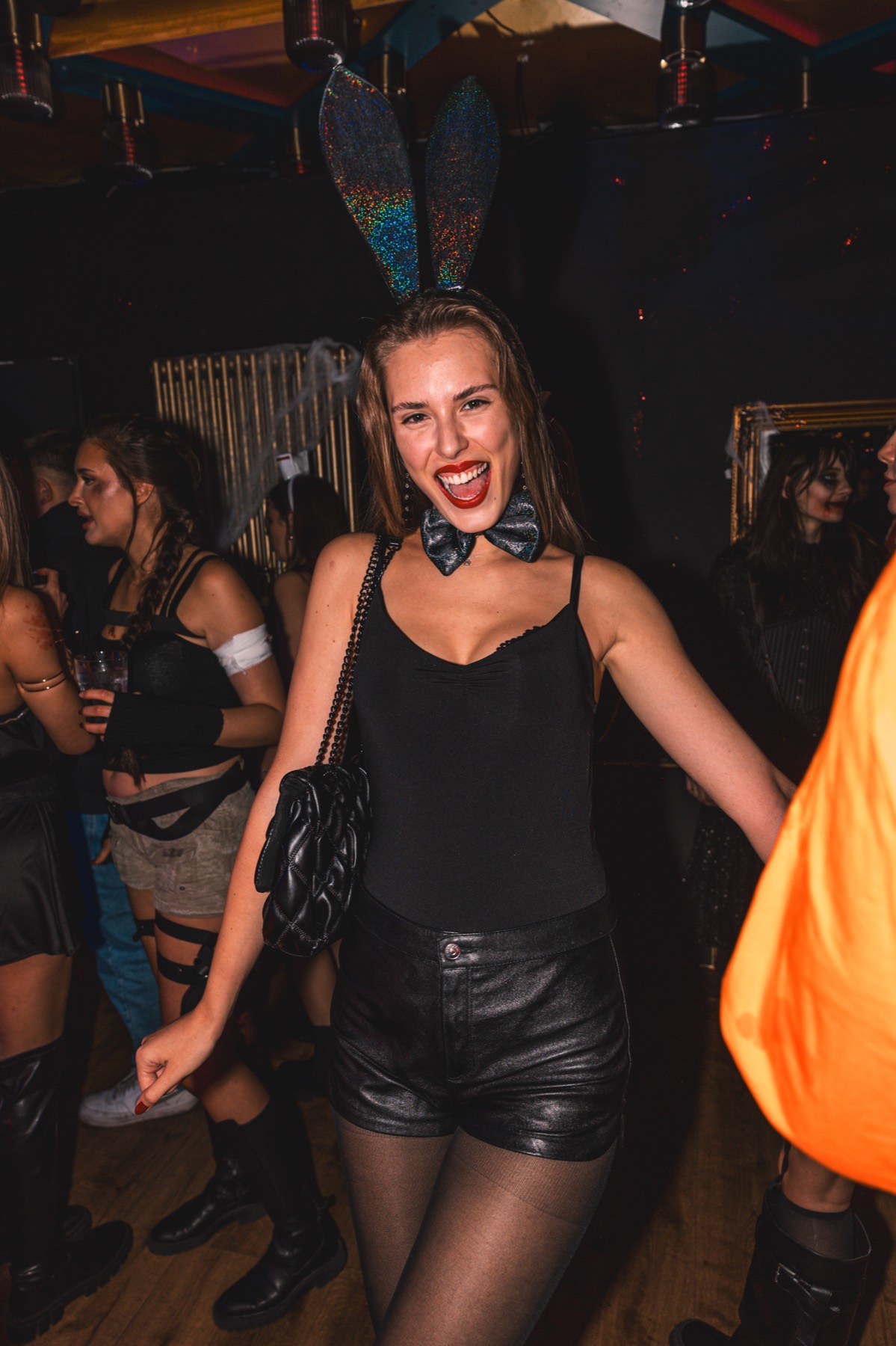 Elegantes Halloween-Kostüm für Frauen: schwarzes Outfit mit Glitzer-Hasenohren und rotem Lippenstift, Spooky Flame Köln