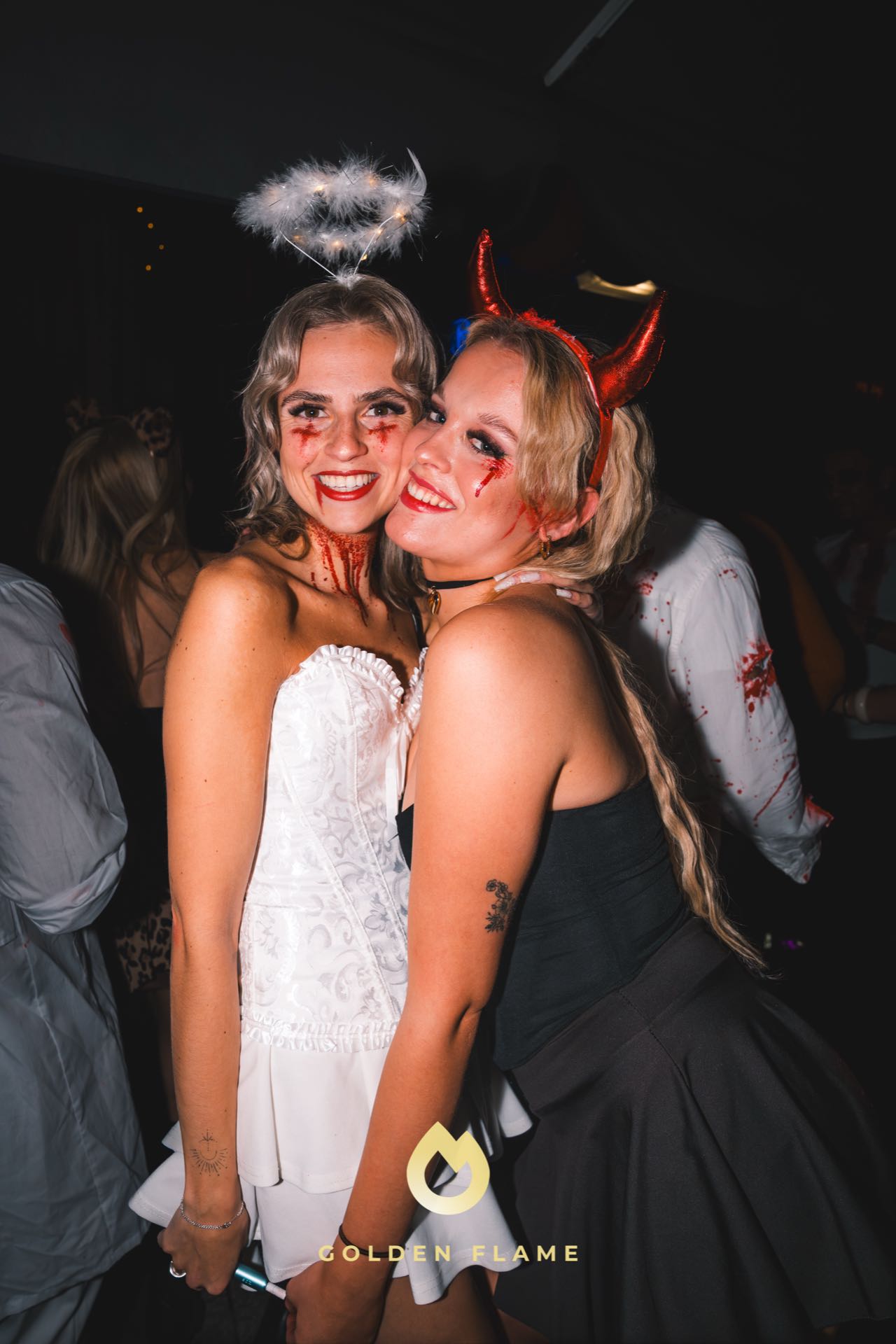 Zwei Freundinnen im Engel- und Teufel-Kostüm bei der Spooky Flame Halloween-Party in Köln, mit direktem Blitz fotografiert