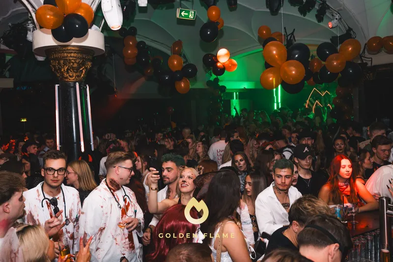 Volle Tanzfläche mit schwarzen und orangenen Ballons und Gästen in blutverschmierten Arztkitteln bei Spooky Flame im Wartesaal am Dom Köln