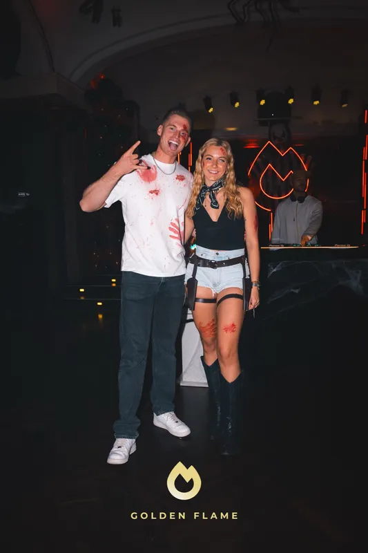 Freund im weißen Shirt mit Kunstblut und Freundin im Cowgirl-Look mit Stiefeln bei Spooky Flame in Köln