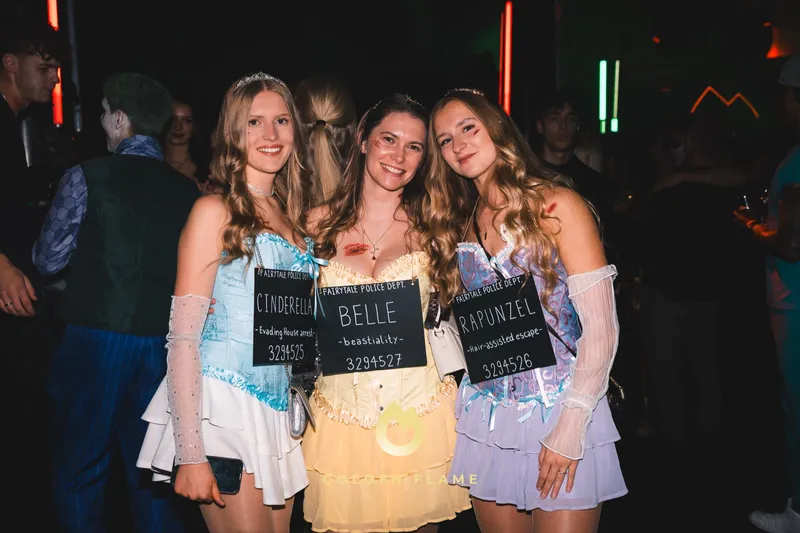 Drei Freundinnen als Cinderella, Belle und Rapunzel mit Polizeifoto-Tafeln bei der Halloween-Party Spooky Flame in Köln