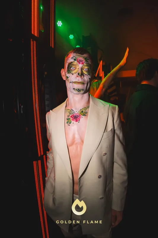 Mann mit buntem Sugar-Skull-Make-up mit Blüten im Gesicht und hellem Anzug bei Spooky Flame in Köln