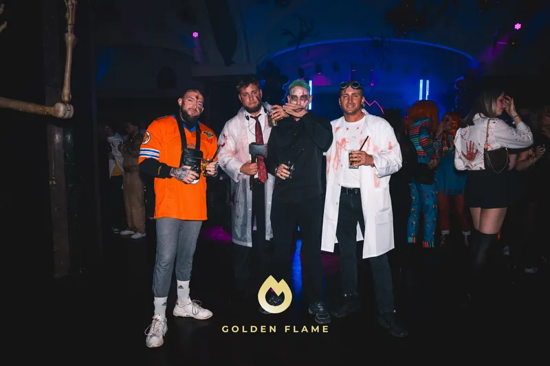 Vier Freunde in schnellen Kostümen mit Arztkittel und Football-Trikot bei der Spooky Flame Halloween-Party in Köln