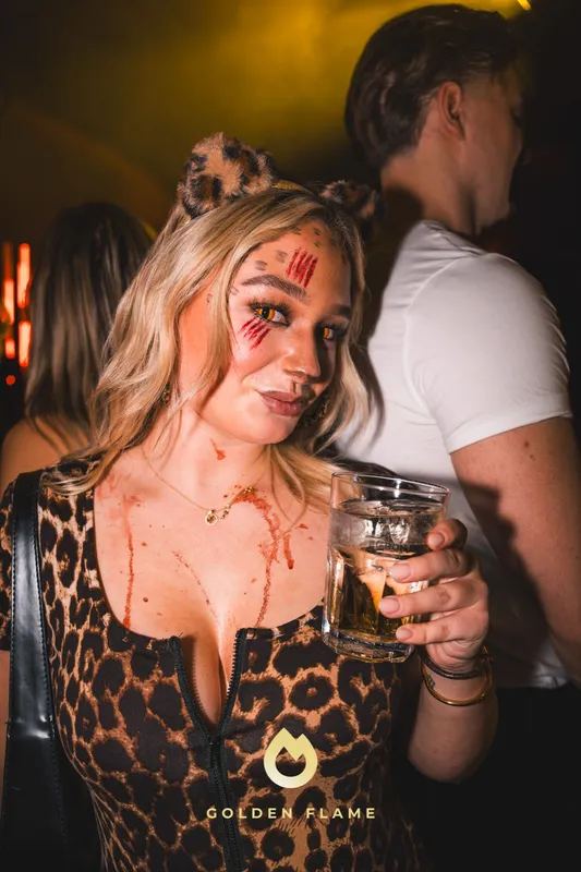 Frau im Leo-Kleid mit gemalten roten Kratzern im Gesicht bei der Halloween-Party Spooky Flame in Köln