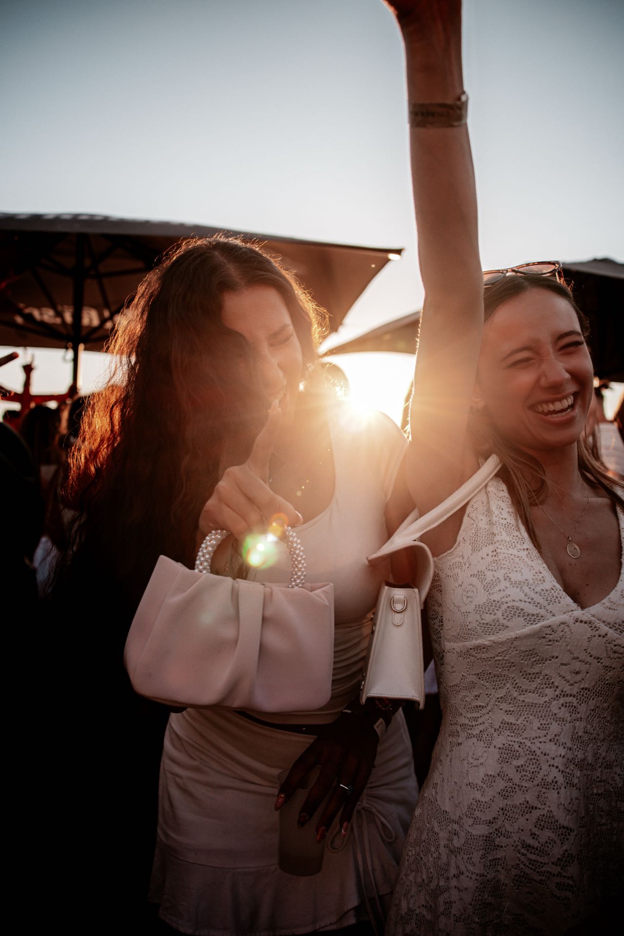 Zwei beste Freundinnen lachen eng beieinander in der Abendsonne beim Golden Flame Open-Air in Köln
