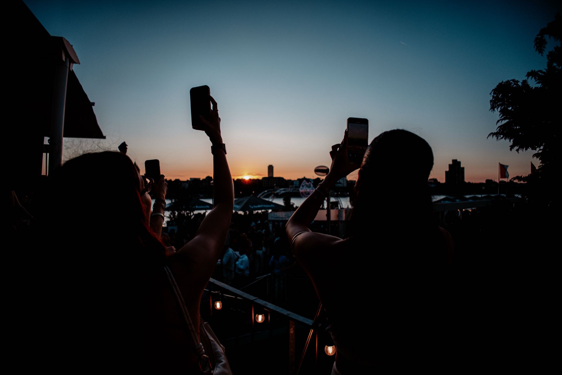Silhouetten fotografieren den Sonnenuntergang mit Handys beim Open Air am Rhein in Köln