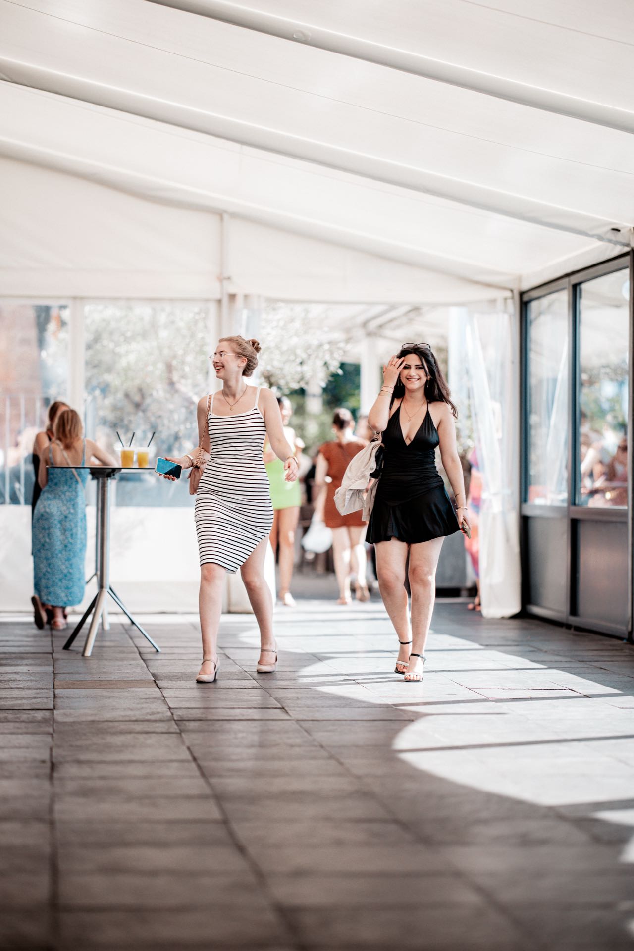 Zwei Freundinnen kommen lachend in Sommerkleidern beim Golden Flame Open-Air an den Rheinterrassen Köln an
