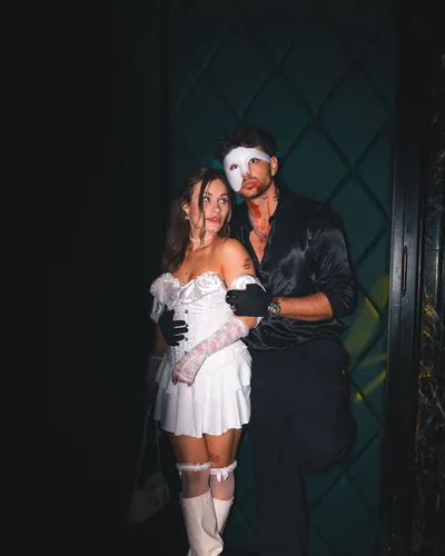 Guest in black with a white Phantom of the Opera mask, next to a white corset dress, at Spooky Flame 2025 in Cologne