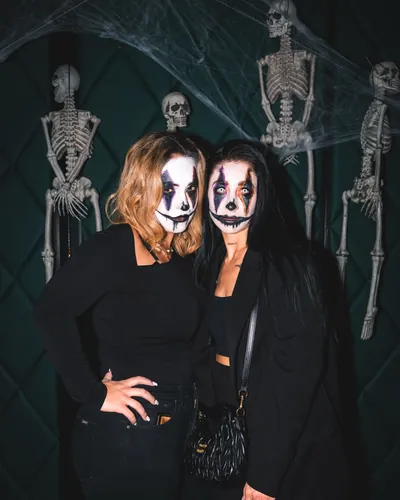 Two guests in black with clown make-up in front of skeleton decorations at Spooky Flame 2025 in Cologne