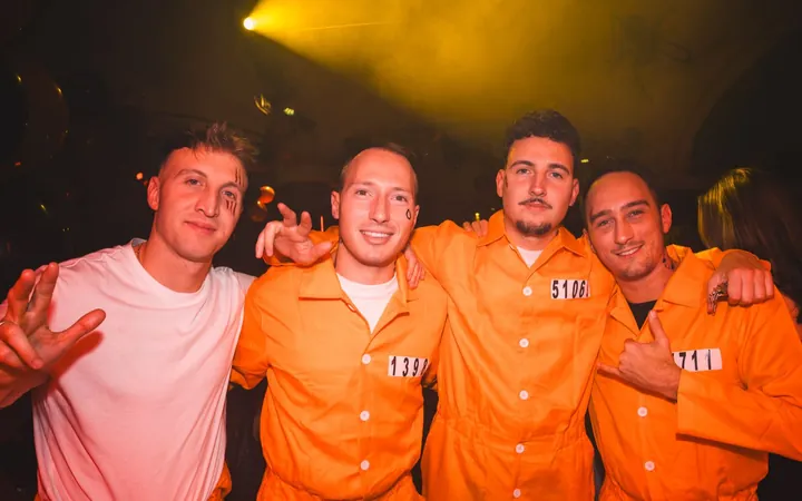 Four guests, three of them as prisoners in orange jumpsuits, at Spooky Flame 2025 at Wartesaal am Dom, Cologne