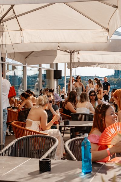 Terrasse der Rheinterrassen Köln am Nachmittag mit Sonnenschirmen und Gästen am Rheinufer