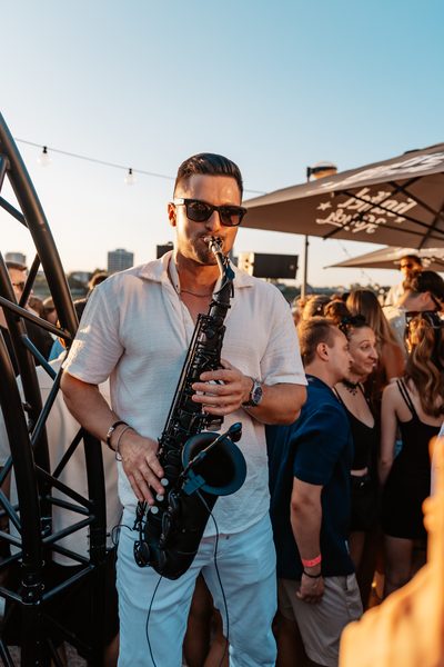 Saxophonist spielt im Abendlicht mitten in der Crowd beim Golden Flame Open-Air Köln