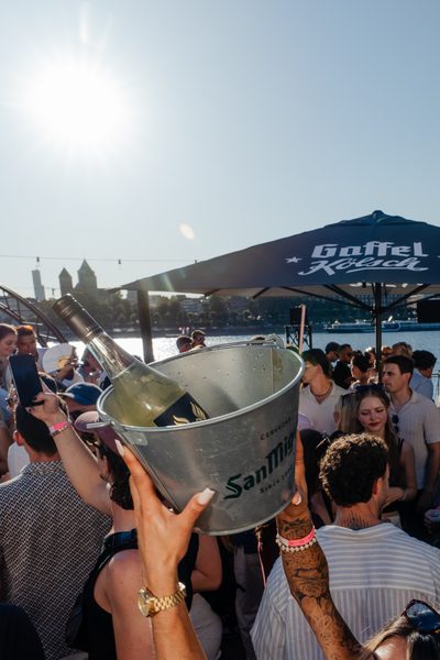 Weinflasche im Eiskübel in der Nachmittagssonne am Rheinufer in Köln mit Blick über den Rhein