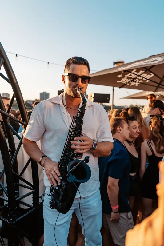 Saxophonist spielt im Abendlicht mitten in der Crowd beim Golden Flame Open-Air Köln