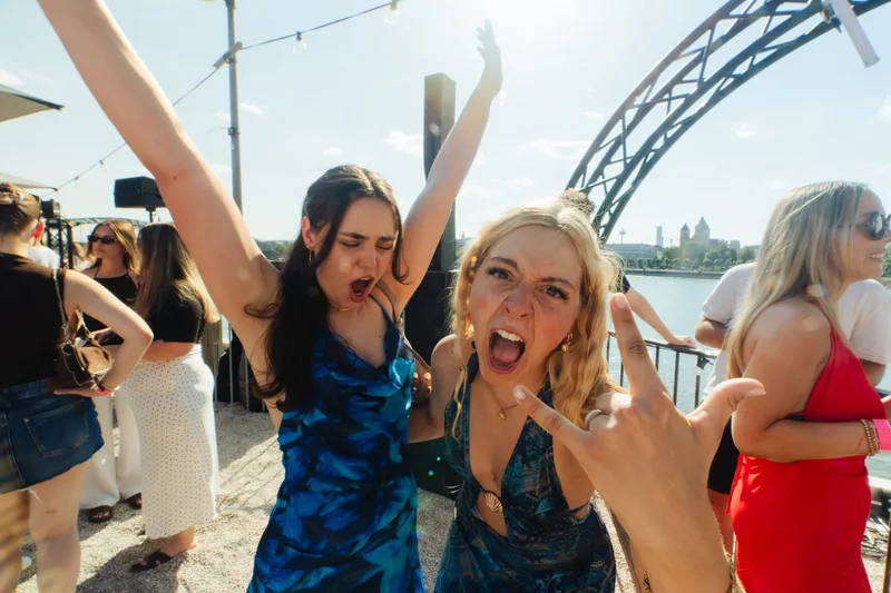 Zwei Freundinnen in Sommerkleidern tanzen ausgelassen beim Open-Air an den Rheinterrassen Köln