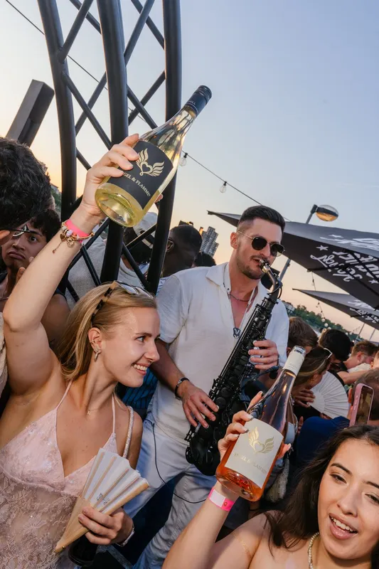 Saxophonist spielt zur goldenen Stunde zwischen den Gästen beim Golden Flame Open-Air an den Rheinterrassen