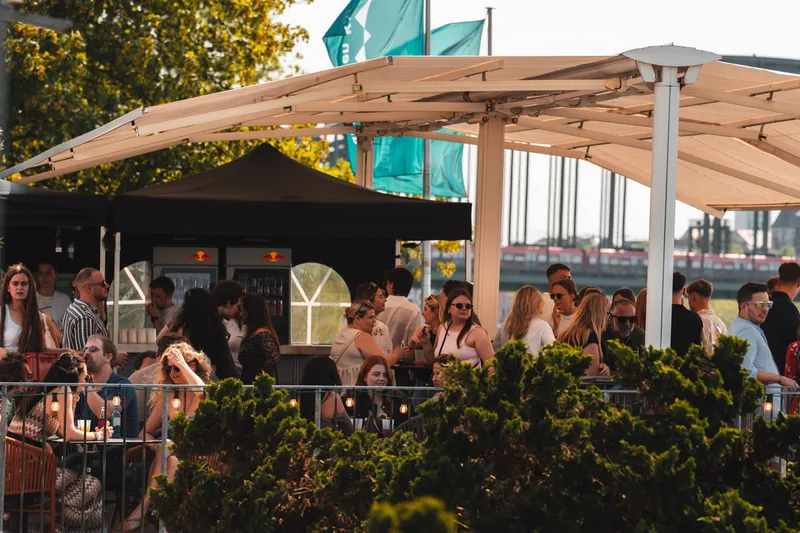 Große Sonnenschirme über einer ruhigen Terrasse am Rhein in Köln