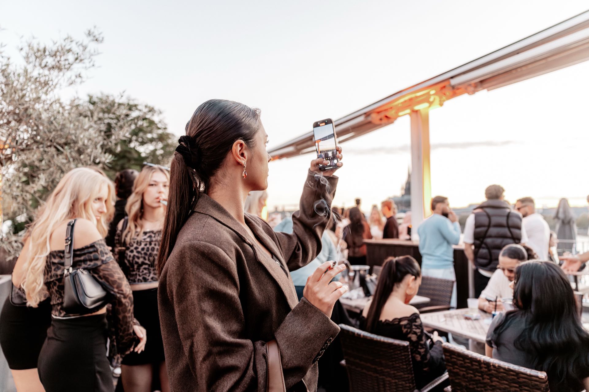 Frau hält den Sonnenuntergang über dem Rhein mit ihrem Handy fest